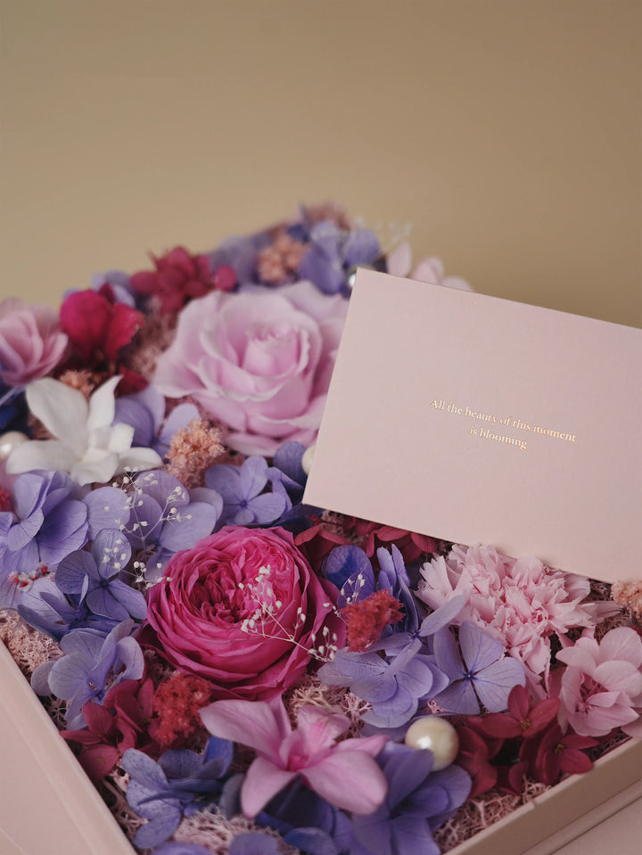 Close-up of lavender and pink preserved roses with hydrangeas and pearl accents