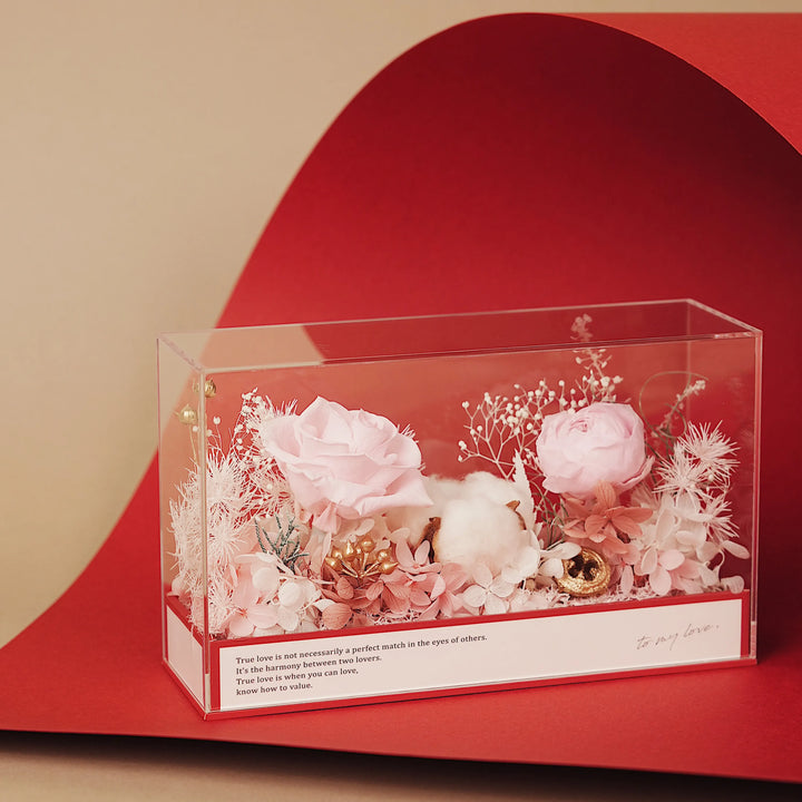 Everlasting Flora Envelope with pink preserved flowers inside a clear box and red envelope base