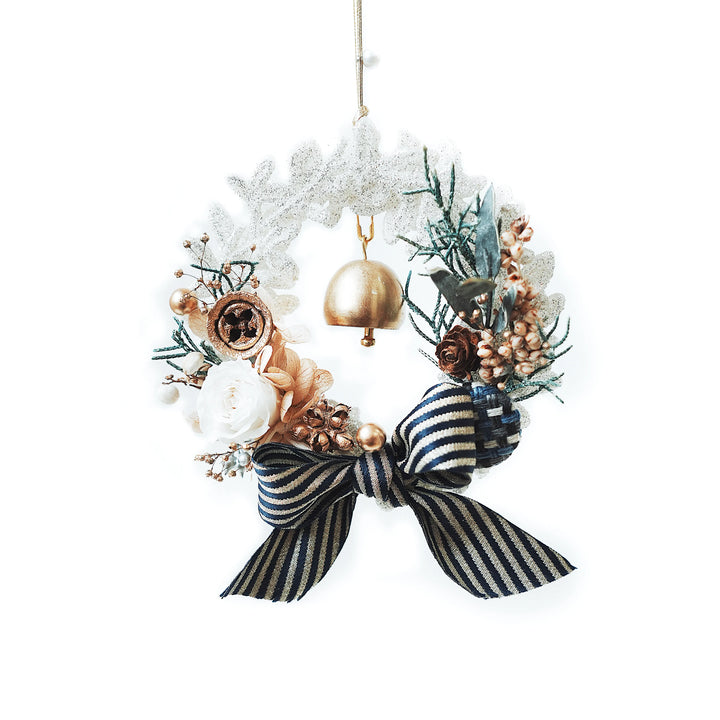 Everlasting Christmas wreath made with preserved roses, hydrangeas, and festive foliage, featuring a striped ribbon bow and golden bell on a white background