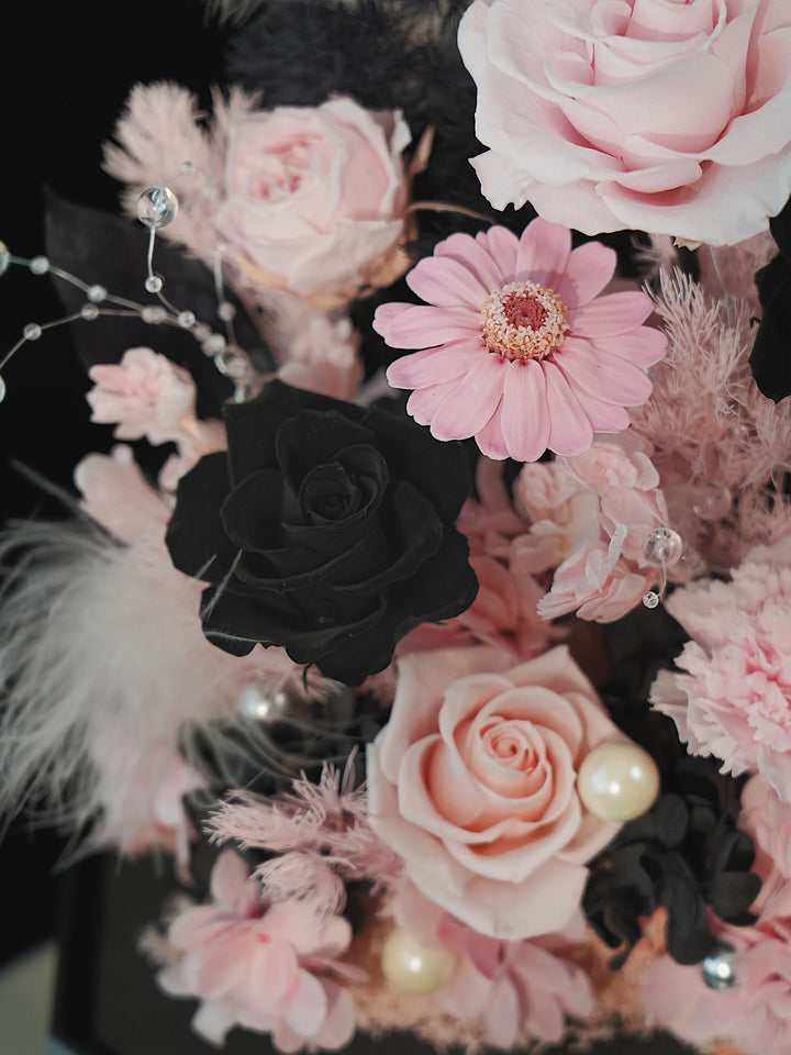 Close-up of a preserved black rose and pink daisy in the Dusky Romance Pink and Black octagon flower box